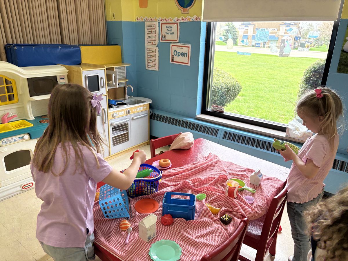 Students at the play kitchen station with toy food at Noah's Ark Preschool Lapeer Michigan